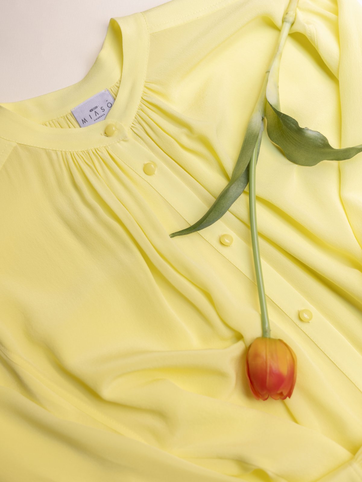 Una blusa Miasō gialla con l'etichetta del marchio